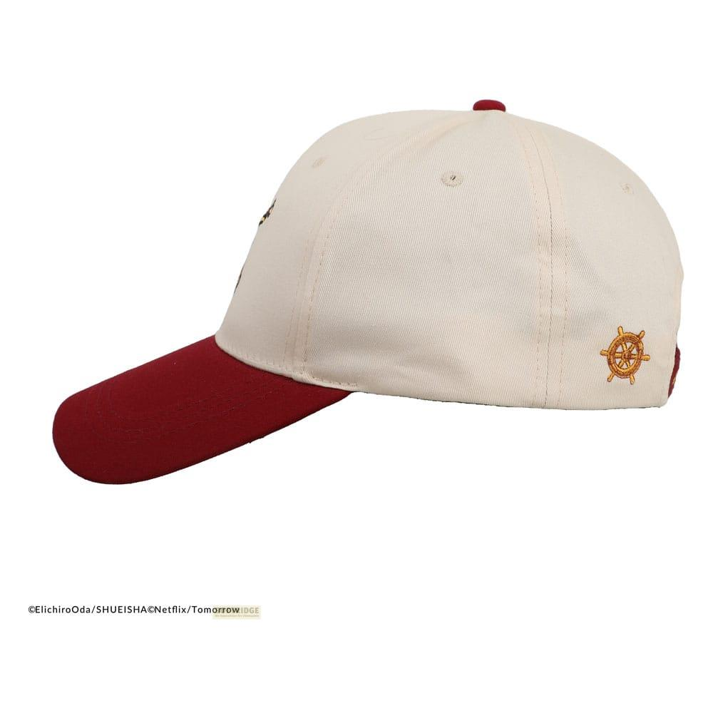 Una gorra crema con visera granate y un emblema de timón dorado.