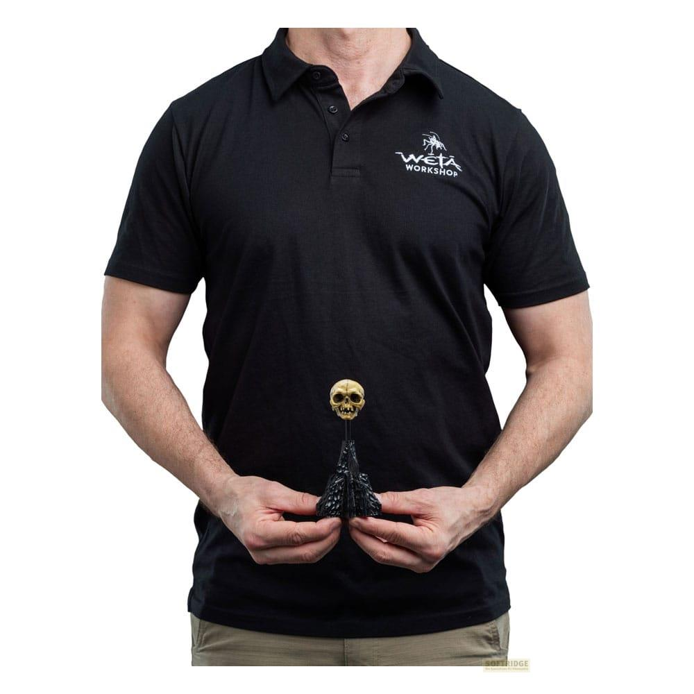 Ein Mann in einem schwarzen Poloshirt hält eine kleine Totenkopfstatue in den Händen.