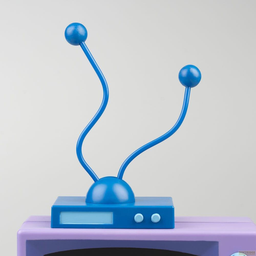 Una antena azul con dos puntas de bola encima de un televisor morado.