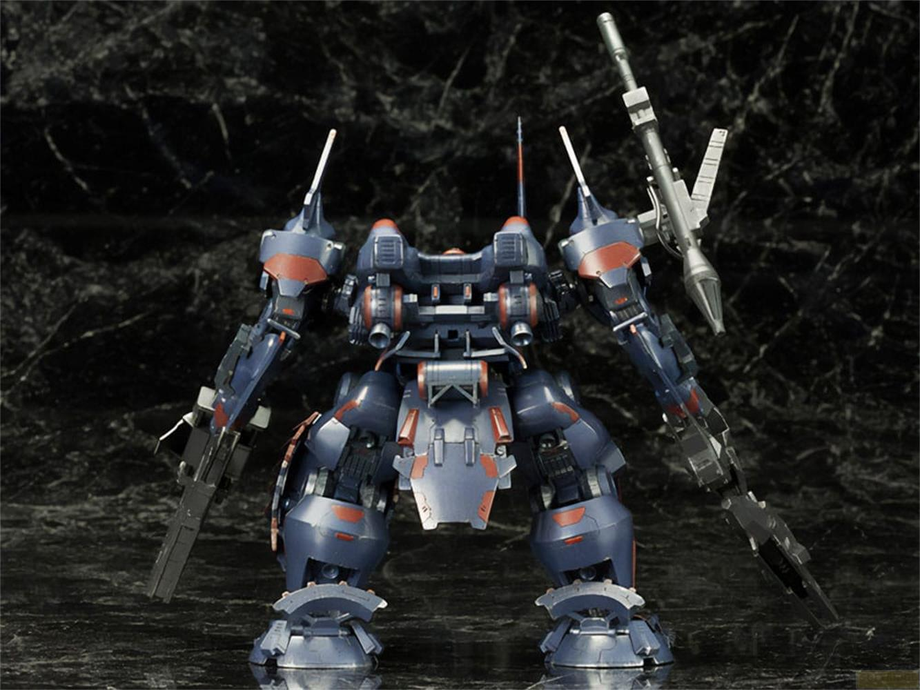 Un mécha bleu et rouge avec des armes se dresse sur fond sombre.