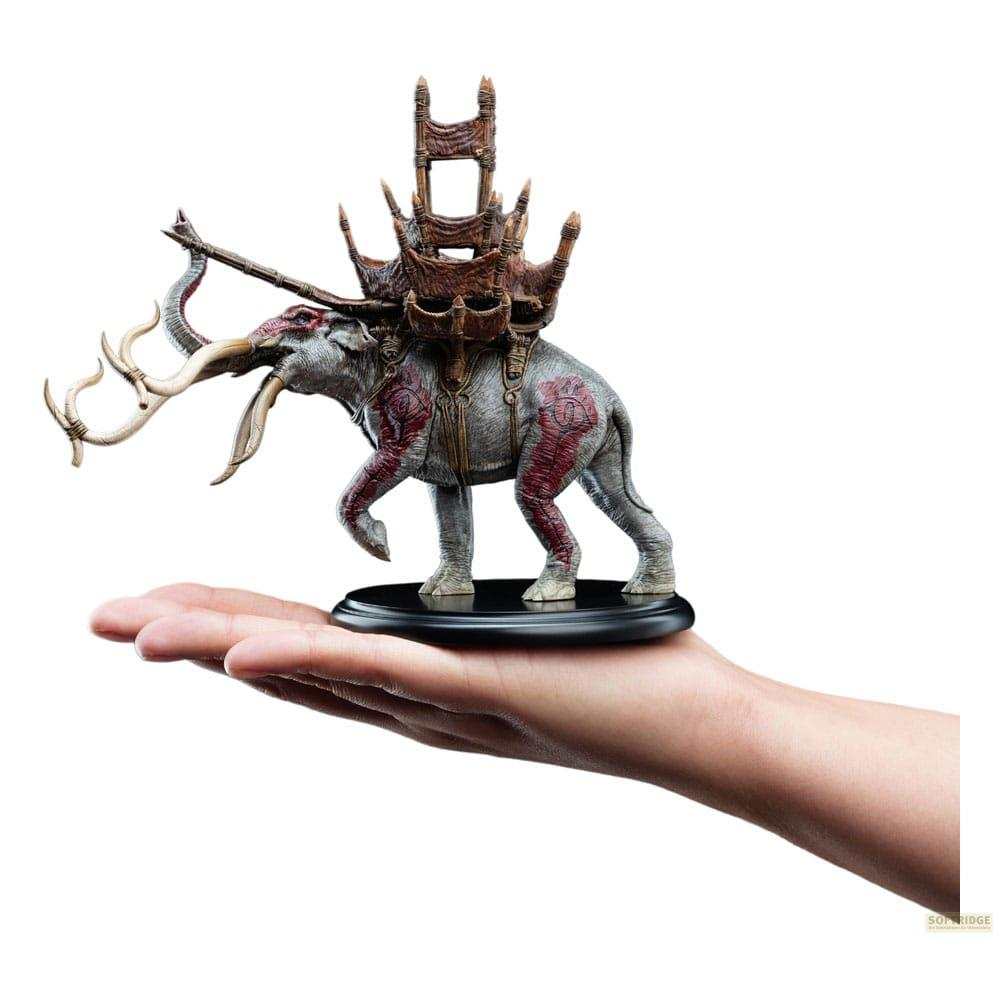 Ein Modell eines grauen Elefanten mit roten Mustern und einem hölzernen Thron auf dem Rücken, gehalten in einer Hand.