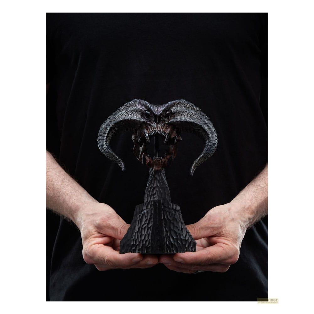 Una persona sostiene una figura detallada de calavera negra con cuernos y dientes.