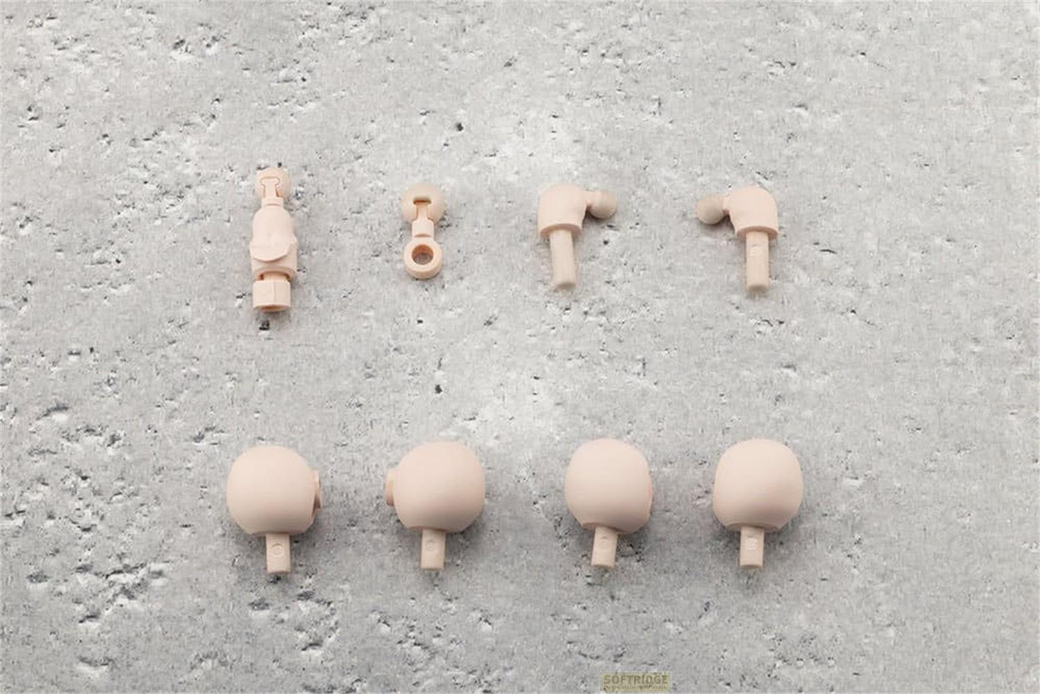 Plusieurs petites pièces en plastique couleur chair pour articulations et têtes disposées sur une texture de pierre grise.