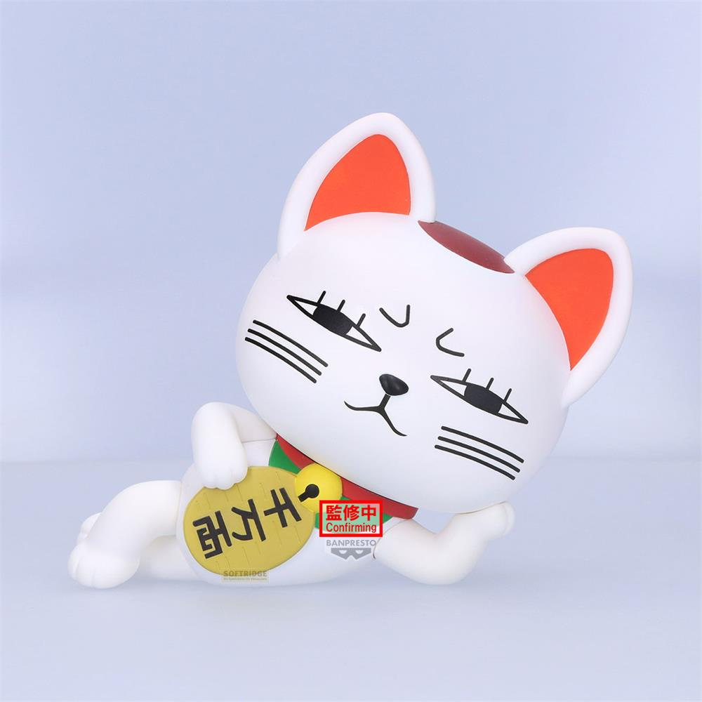 Una figura blanca de Maneki-neko con orejas naranjas yace de lado.
