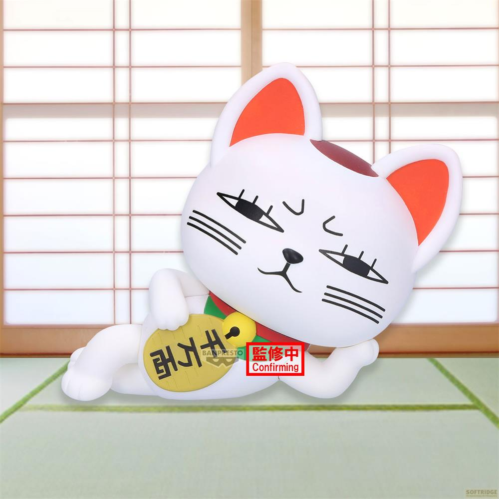 Una figura blanca de Maneki-Neko con orejas rojas yace sobre una alfombra verde.