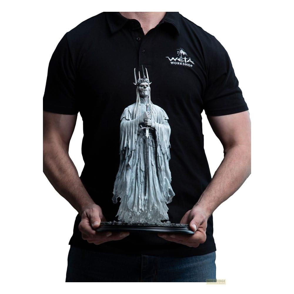 Hombre sostiene detallada figura del Rey Brujo con corona y espada.