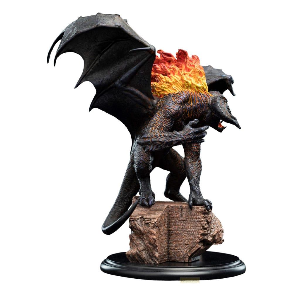 Un drago scuro con ali e fiamme sulla schiena sta su una roccia.