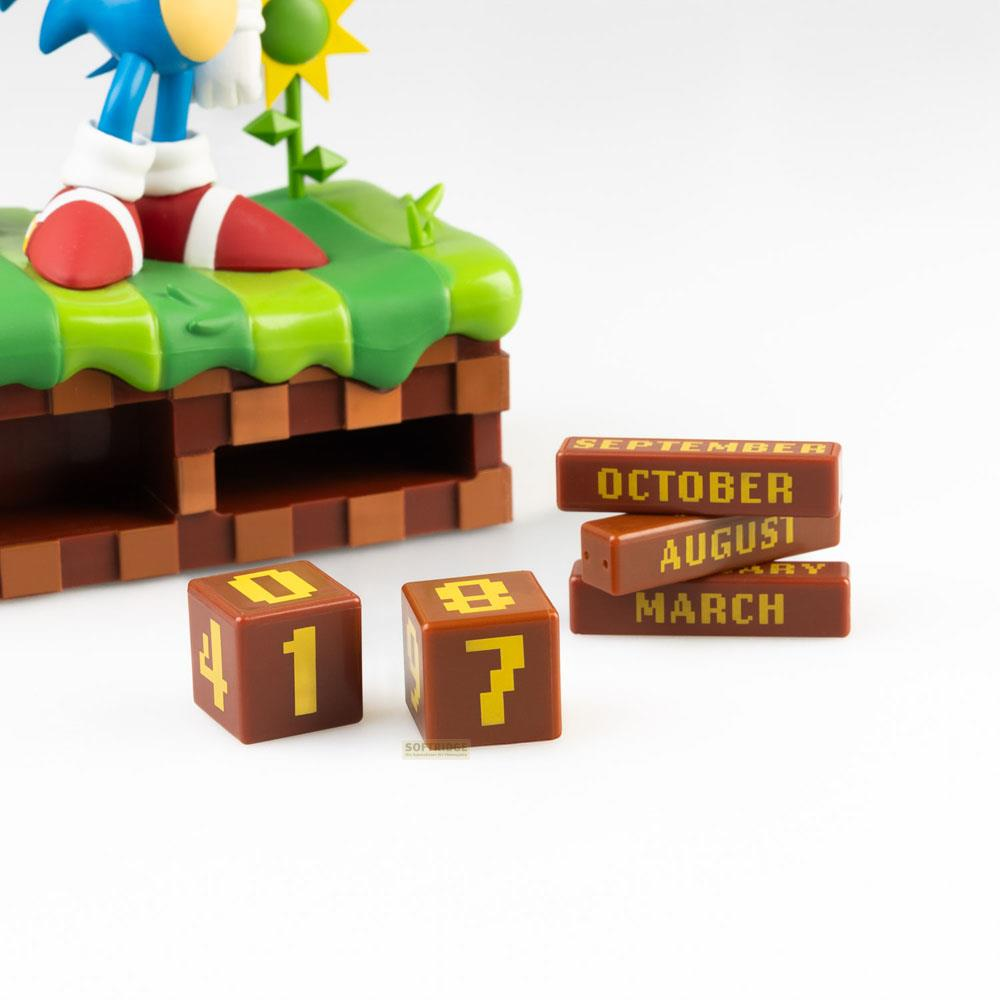 La figura de Sonic está sobre una base de colina verde con bloques marrones. Dados muestran 1 y 7.