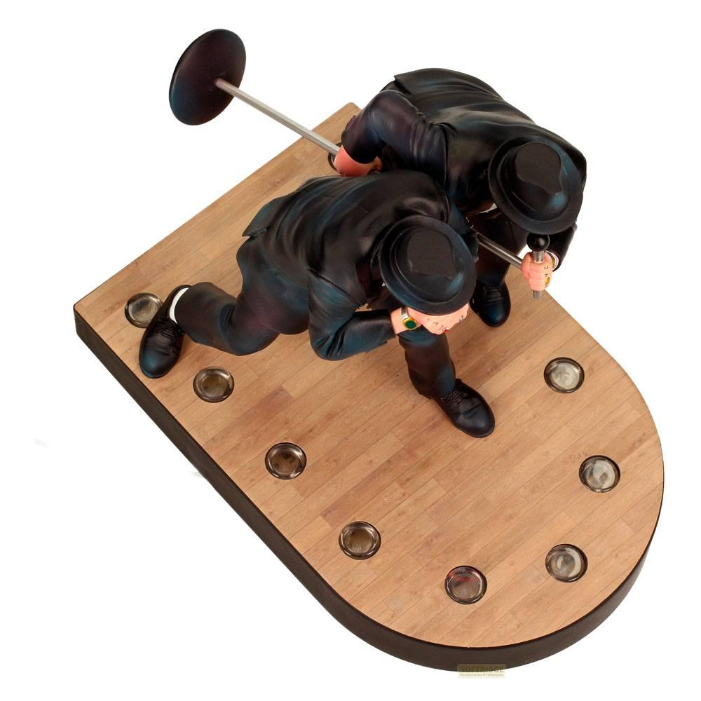 Dos hombres con trajes y sombreros se inclinan sobre un juego de billar en mesa de madera.