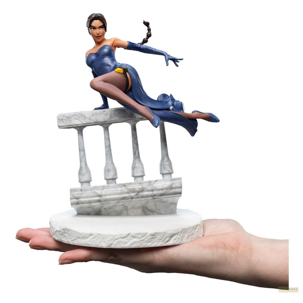 Figur einer Frau in blauem Kleid auf Marmorsockel, gehalten von einer Hand.