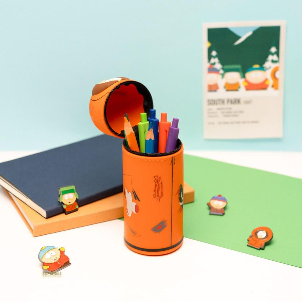 Un portalápices naranja con bolígrafos, figuras de South Park y libros.