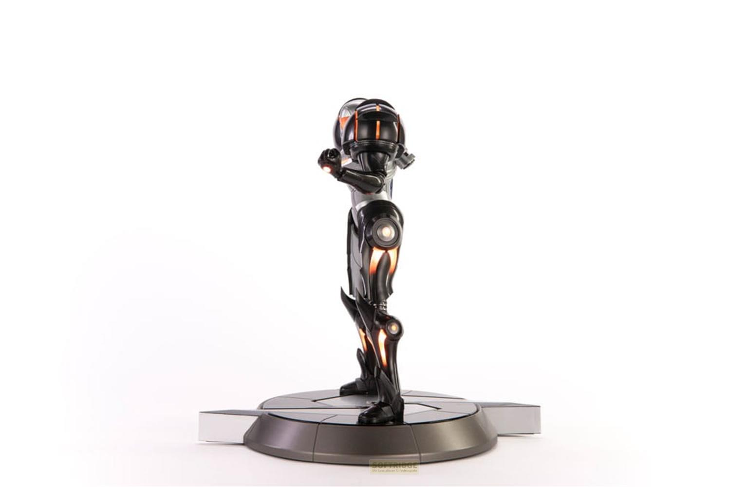 Eine dunkle Figur in Rüstung mit orangen Akzenten steht auf einer metallischen Basis.