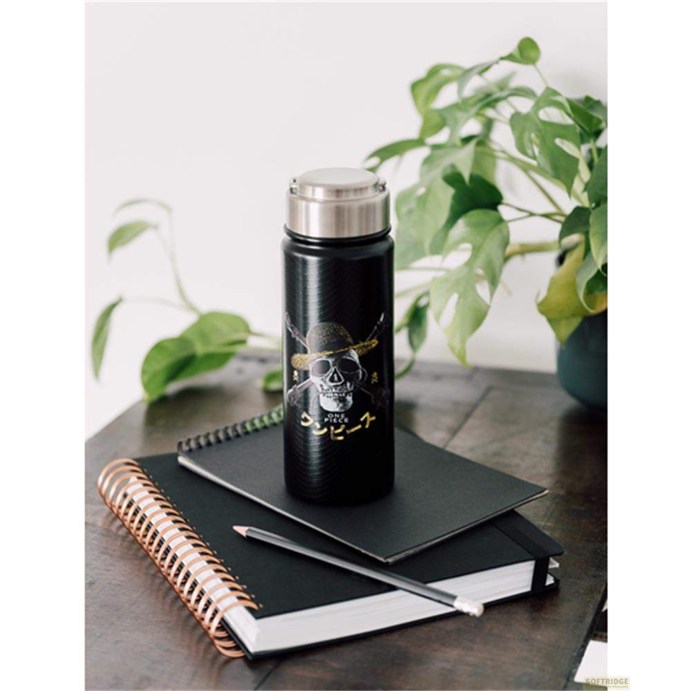 Termo negro con diseño de calavera sobre cuadernos.