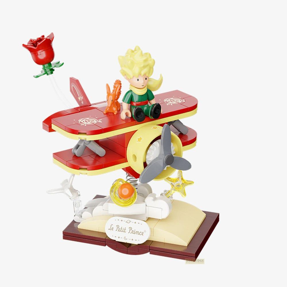 Modelo de juguete El Principito: niño en biplano con rosa, zorro y libro.