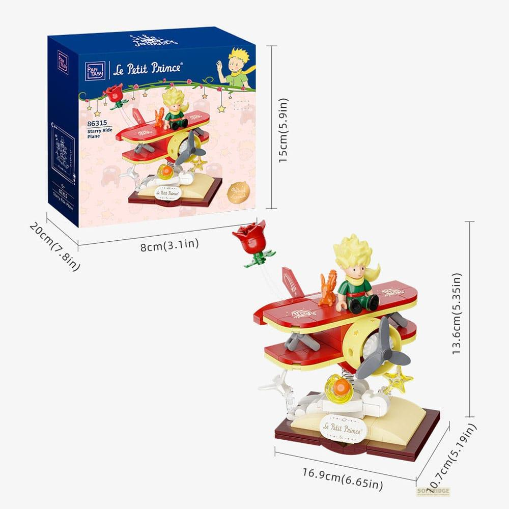 Juego de Le Petit Prince con biplano rojo, rosa y figura de príncipe. Caja mostrada.