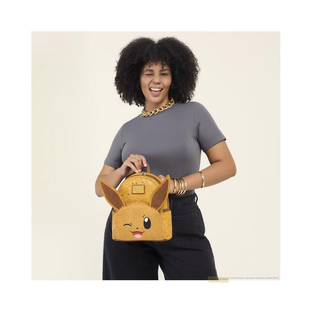 Una mujer con pelo rizado sostiene una mochila amarilla de Eevee.