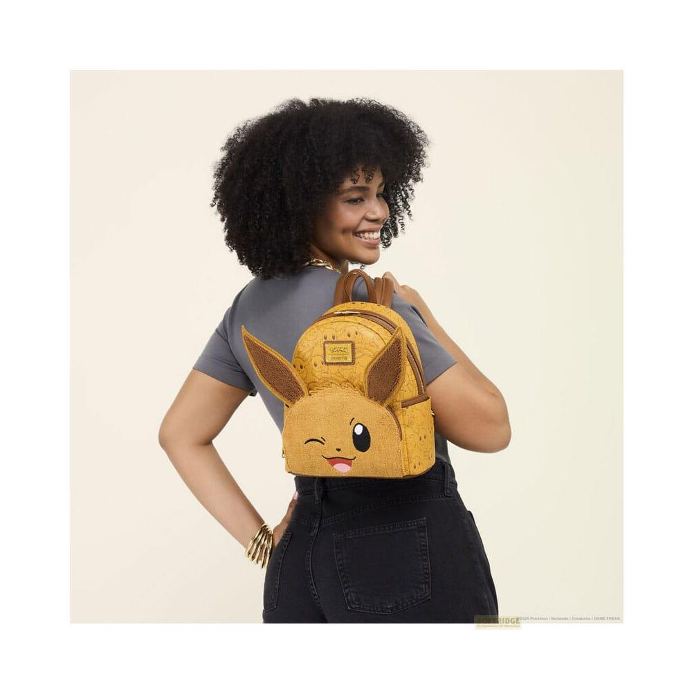 Una mujer con pelo rizado lleva una mochila amarilla con Eevee.
