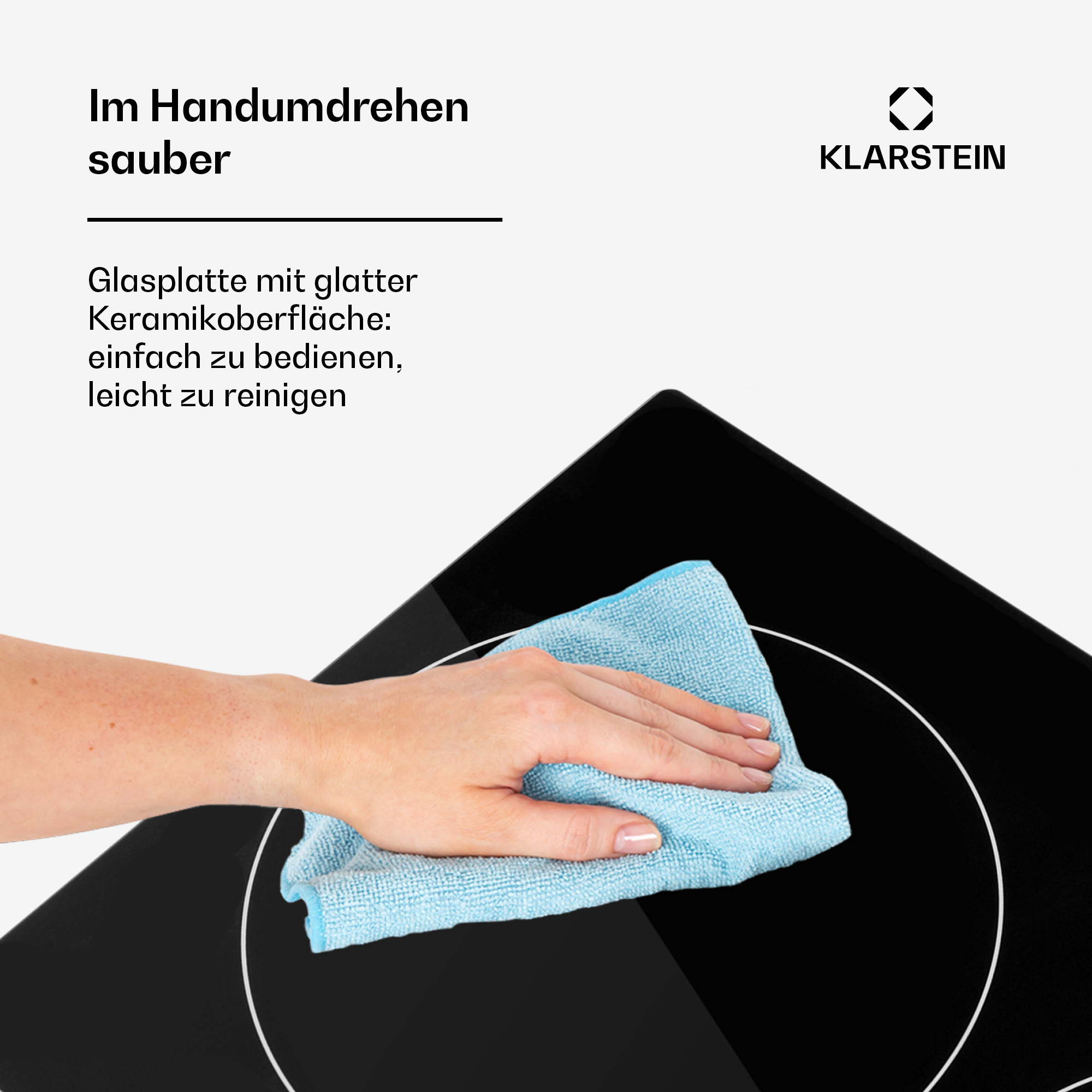 Eine Hand wischt mit einem blauen Tuch über eine schwarze Kochplatte.