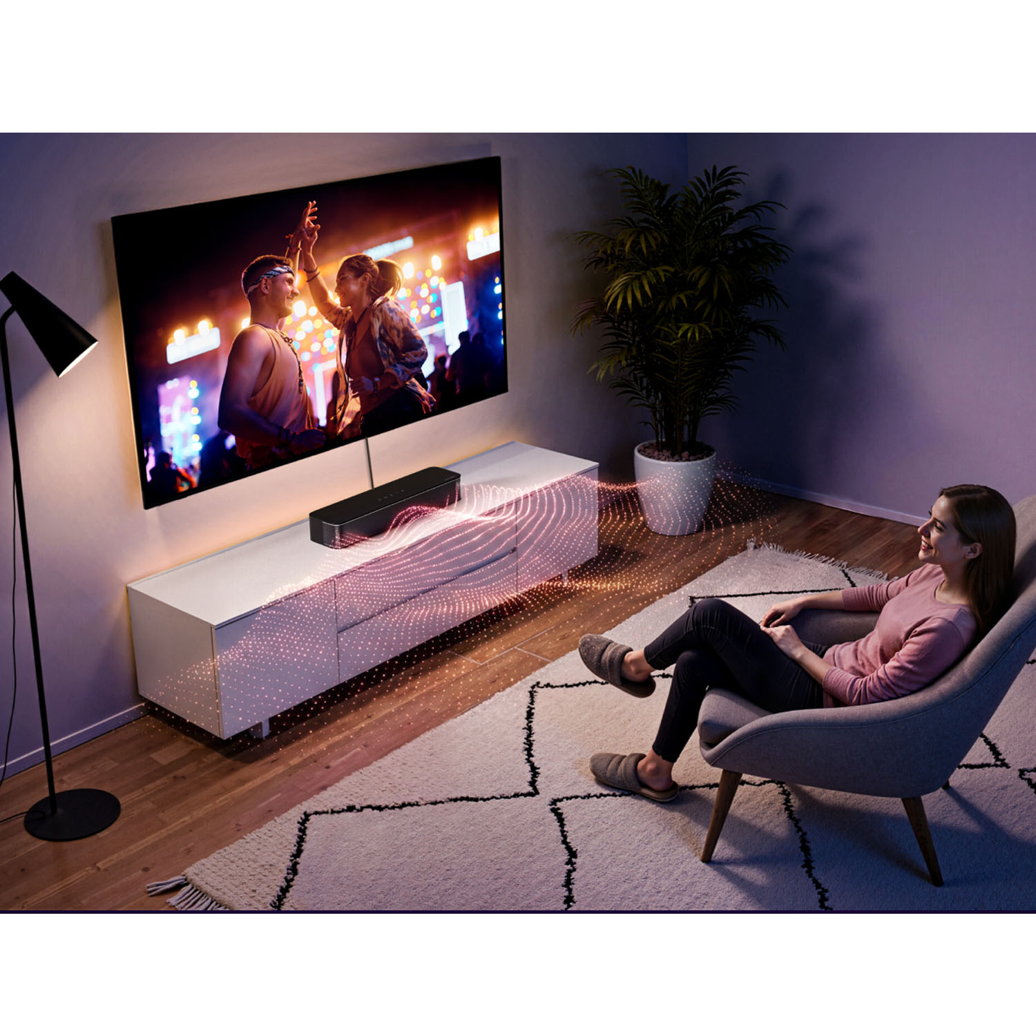 Femme dans fauteuil regarde concert TV. Barre de son émet ondes lumineuses.