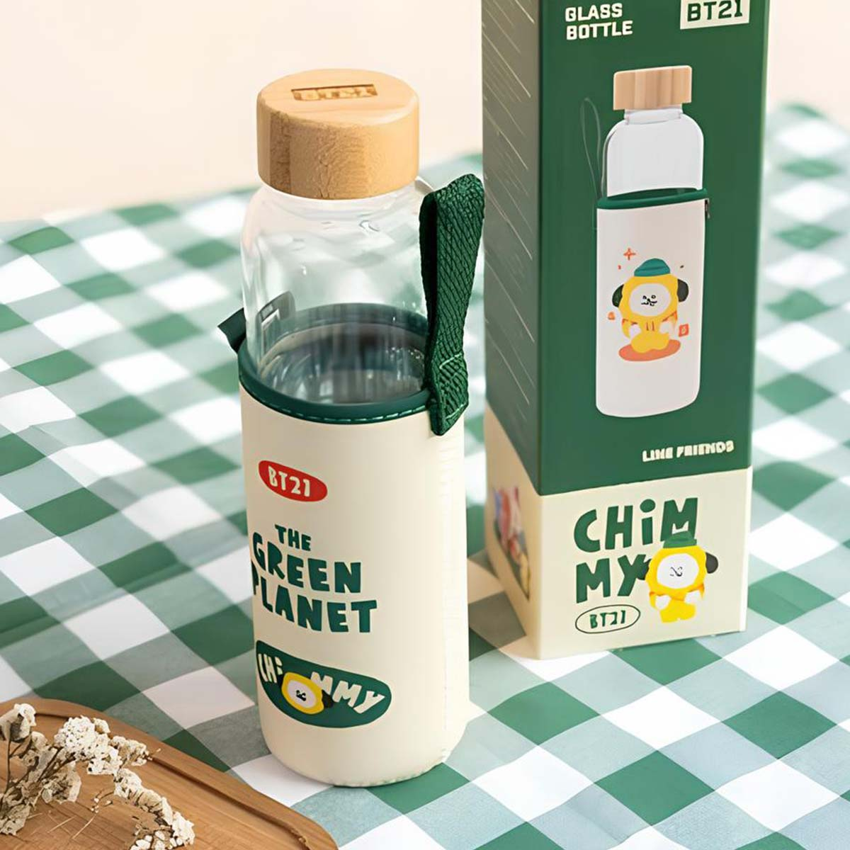 Una bottiglia di vetro con tappo in bambù e manico verde, accanto a una scatola BT21.