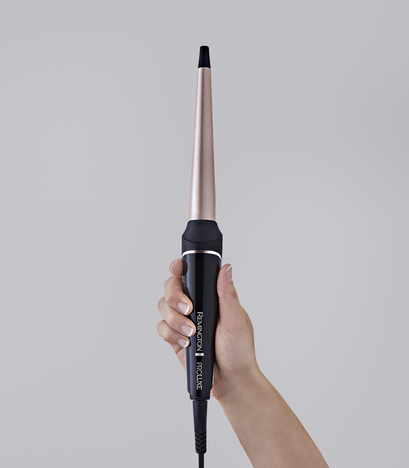 Dłoń trzyma czarną lokówkę z stożkowym, różowo-złotym wałkiem.