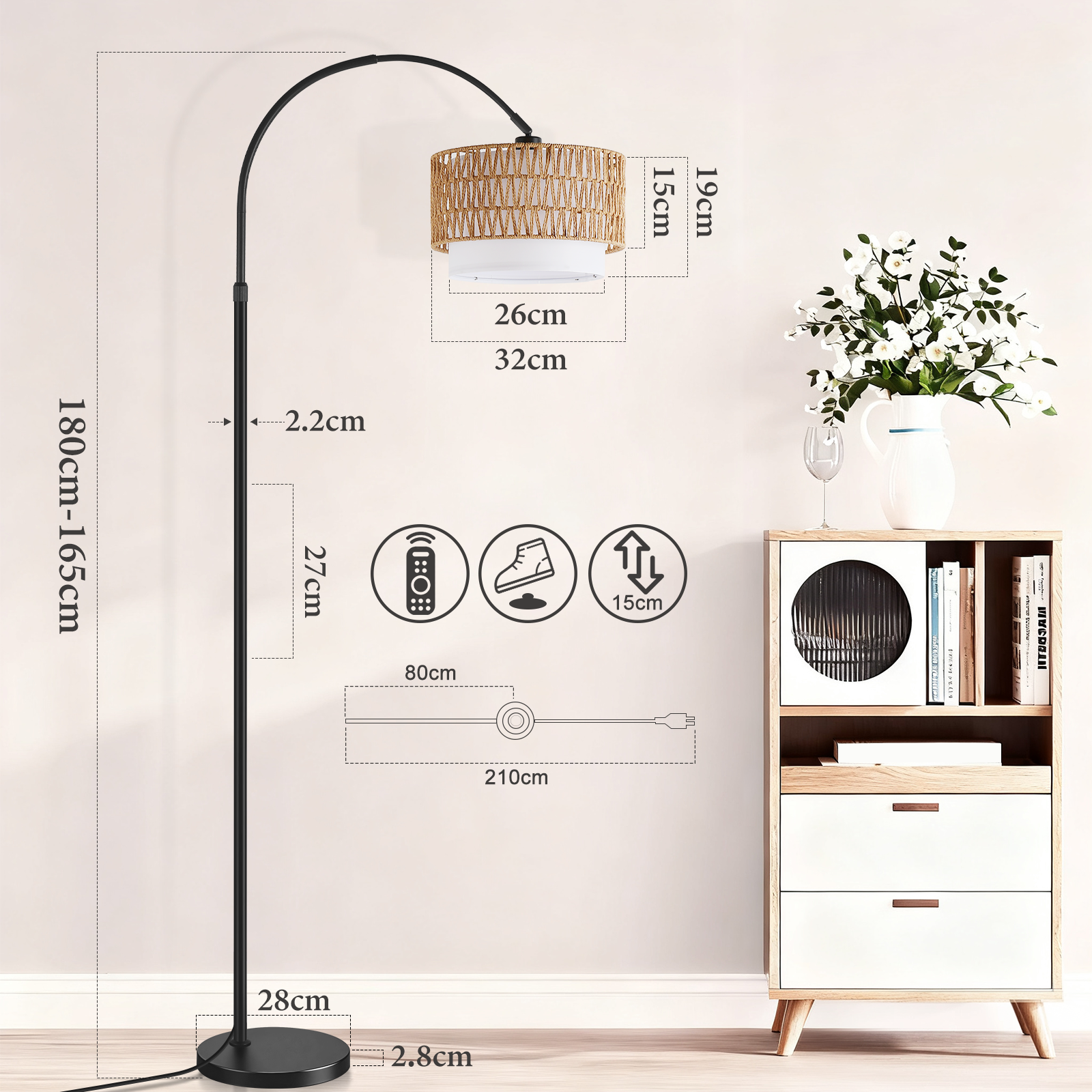 Una lampada da terra ad arco nera con paralume intrecciato si trova accanto a un mobile bianco con fiori.