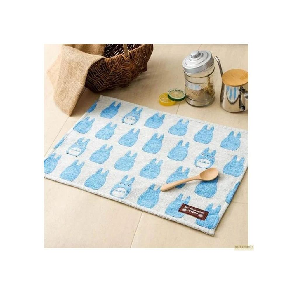 Un tissu bleu à motifs Totoro est posé au sol. Une cuillère en bois repose dessus.