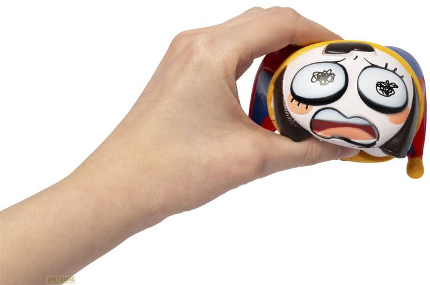 Una mano sujeta una pelota blanda con cara de sorpresa, blanco, amarillo, rojo, azul.