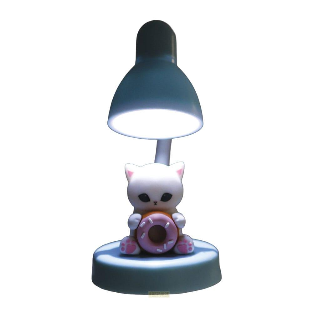 Eine weiße Katze hält einen rosa Donut vor einer eingeschalteten Lampe.