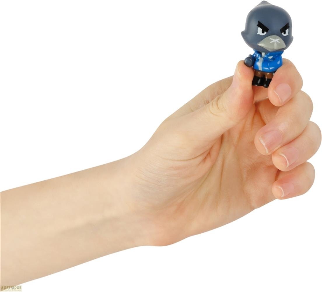 Une main tient une petite figurine d'oiseau portant une veste bleue.