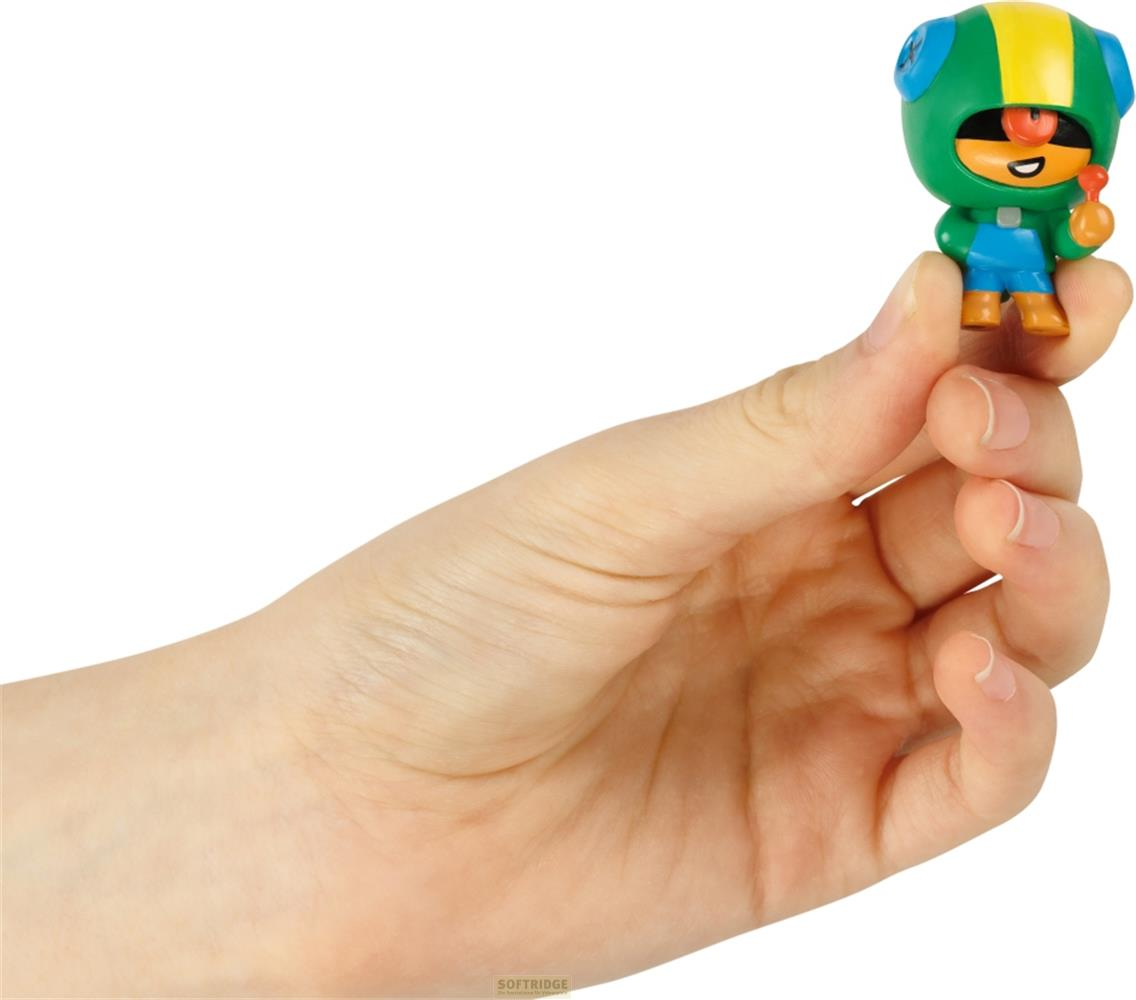 Une figurine verte au casque jaune et aux vêtements bleus est tenue par une main.