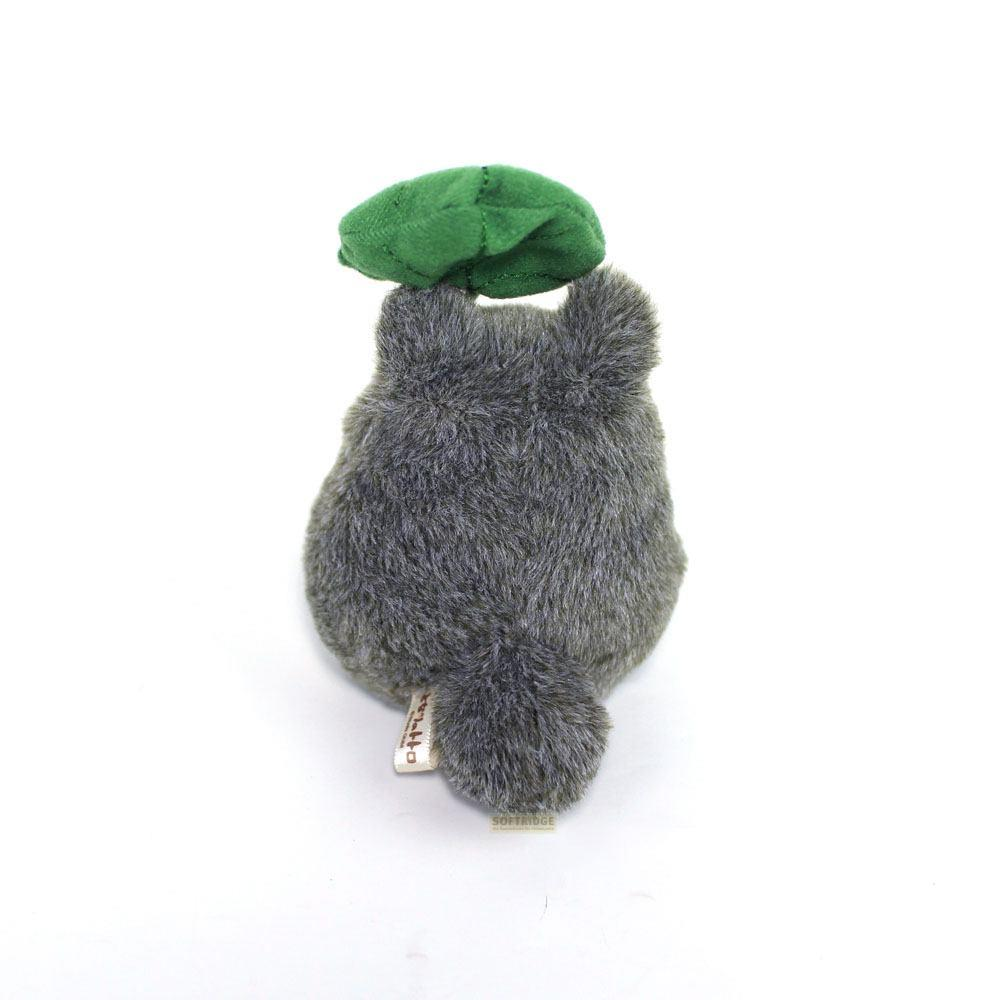 Peluche Totoro grise avec une casquette verte, vue de dos sur fond blanc.