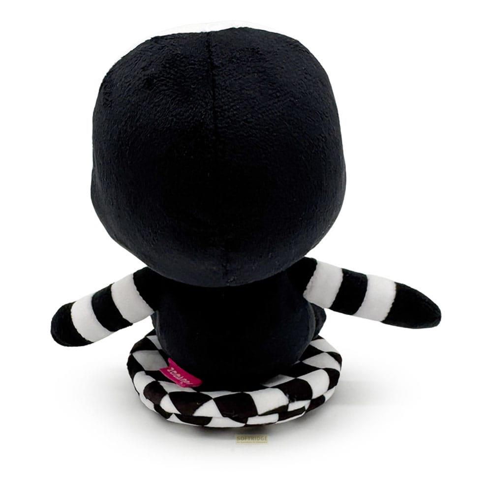 Une peluche noire à rayures blanches assise sur un motif damier.