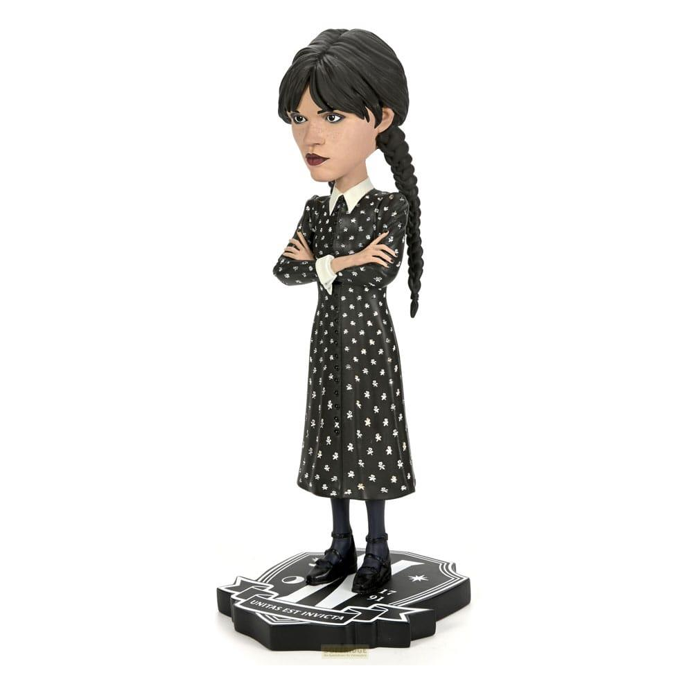 Figura de Wednesday Addams con vestido negro y estampado blanco, brazos cruzados.