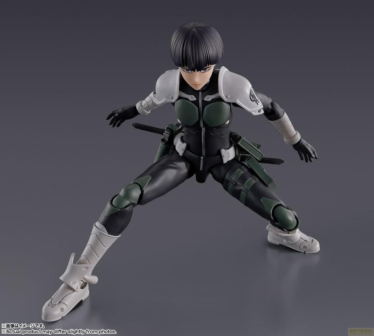 Action figure in tuta scura con accenti verdi/bianchi, in posa dinamica.