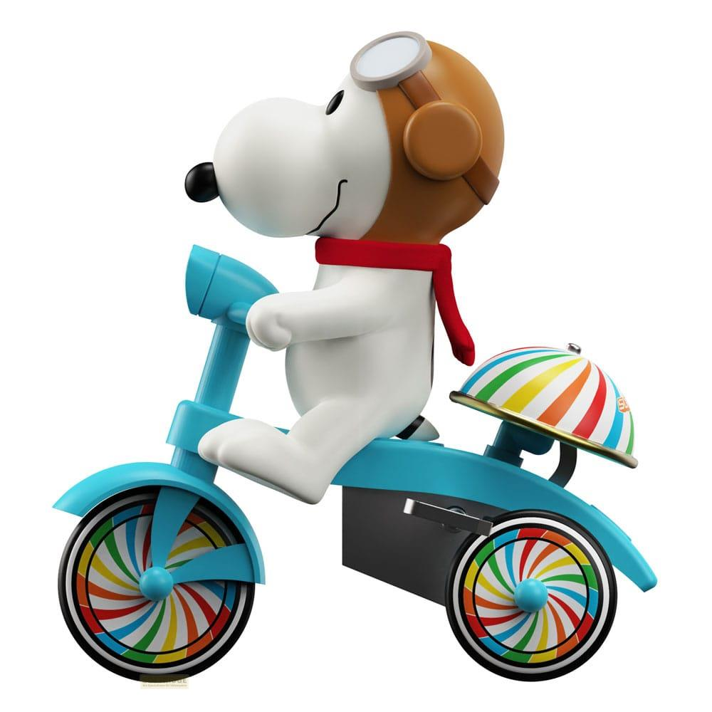 Snoopy guida un triciclo blu con ruote colorate e casco arcobaleno.