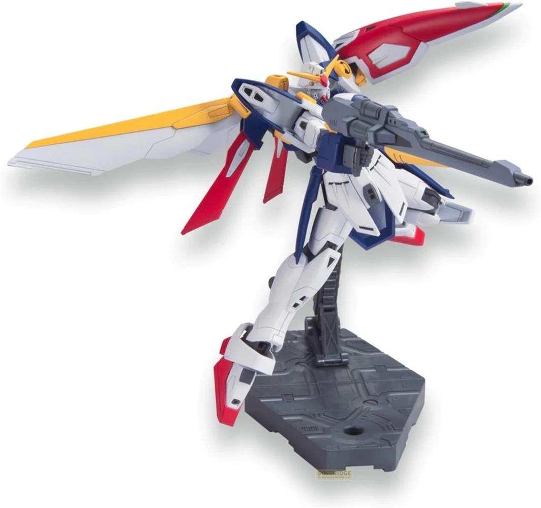 Un robot blanc, bleu et rouge avec des ailes et un pistolet, posé sur un support.
