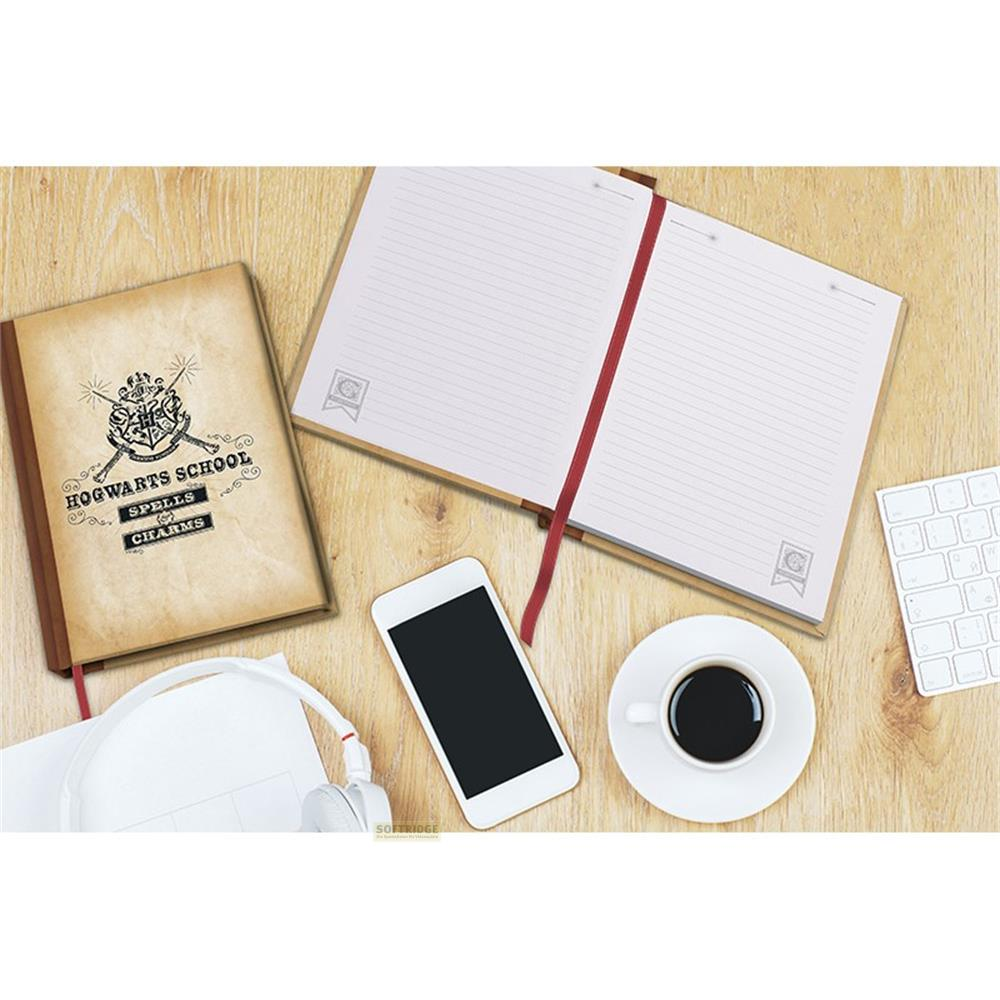 Journal de Poudlard, carnet ouvert, téléphone, café, casque et clavier sur bois.