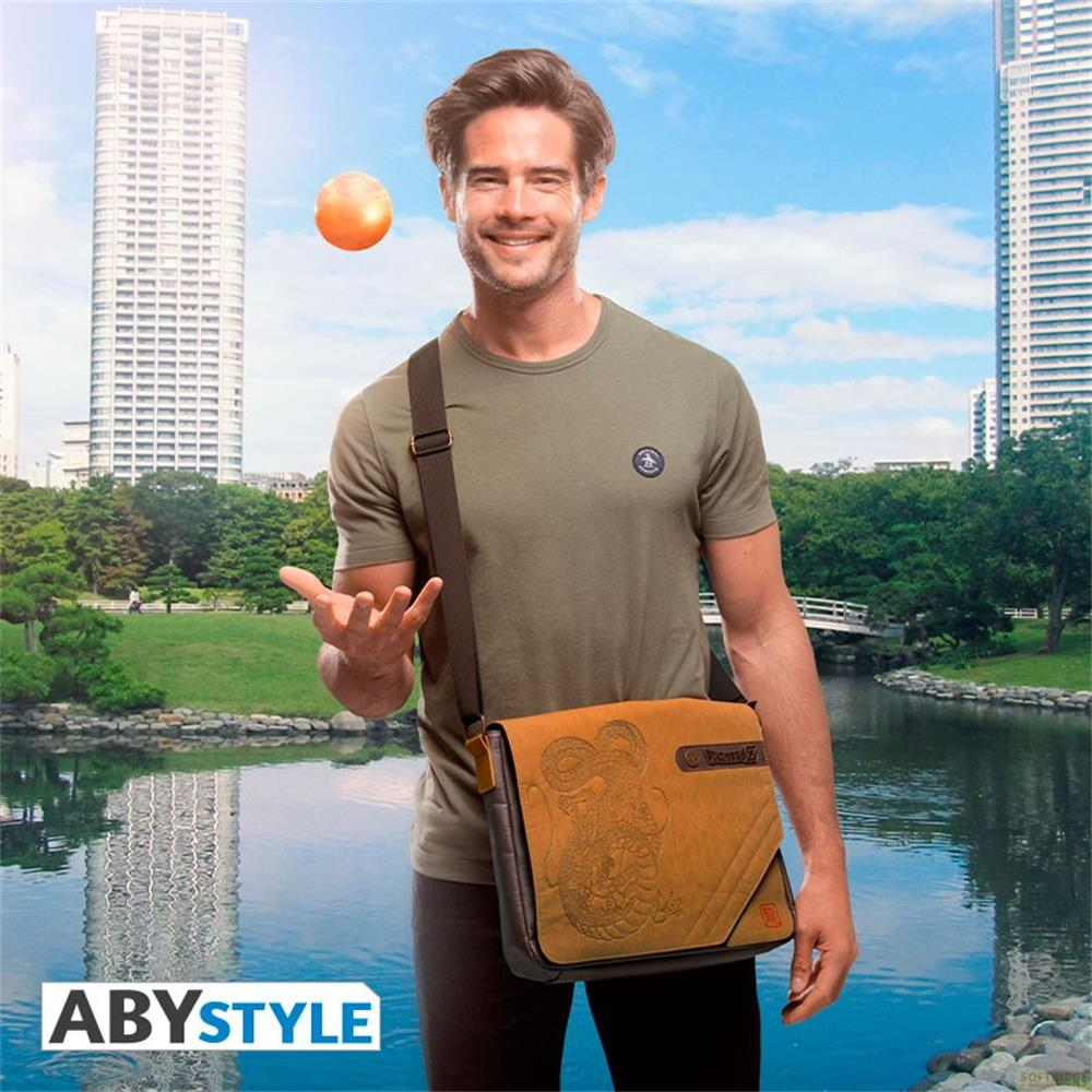 Homme avec sac lance balle dans parc avec gratte-ciel et étang.