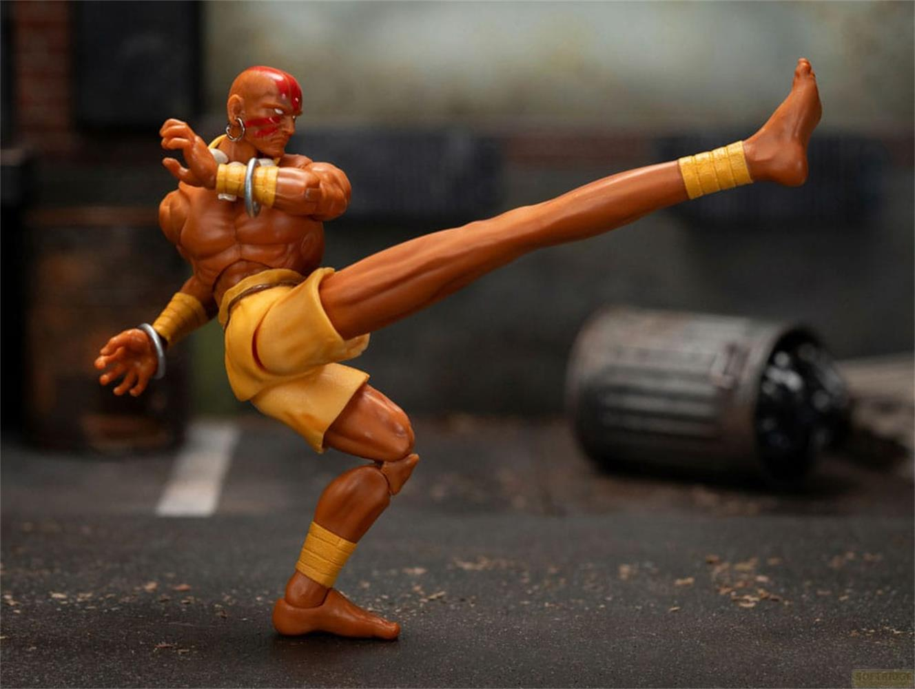 Action figure in posa di combattimento, gamba estesa, con pantaloncini gialli.