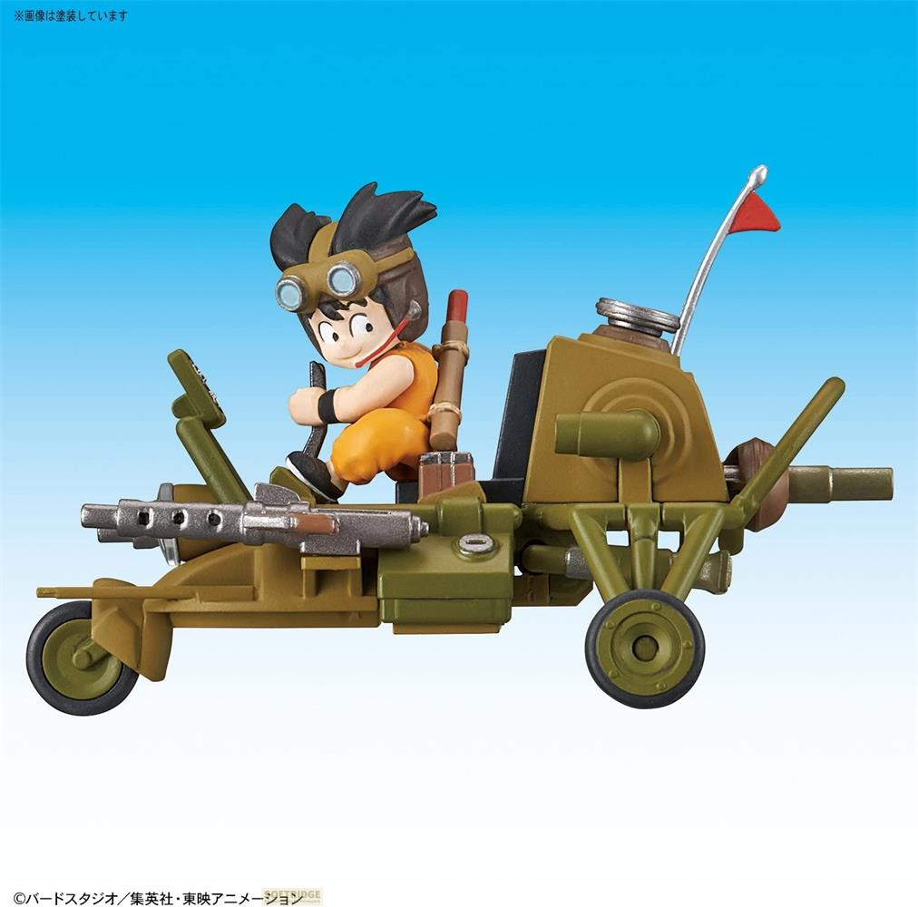 Un garçon avec des lunettes conduit un véhicule vert olive à trois roues avec des armes.