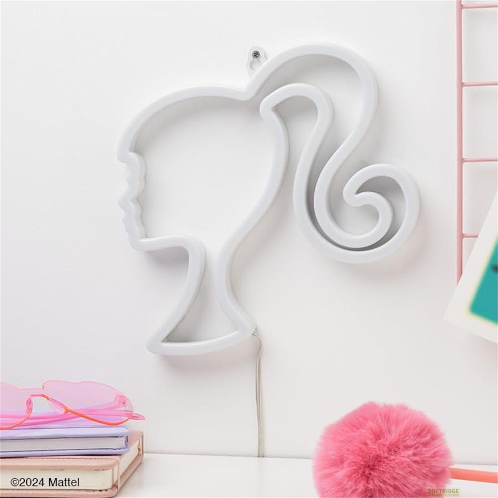 Una luz de neón blanca con forma de cabeza de Barbie en una pared, con libros y gafas de sol abajo.