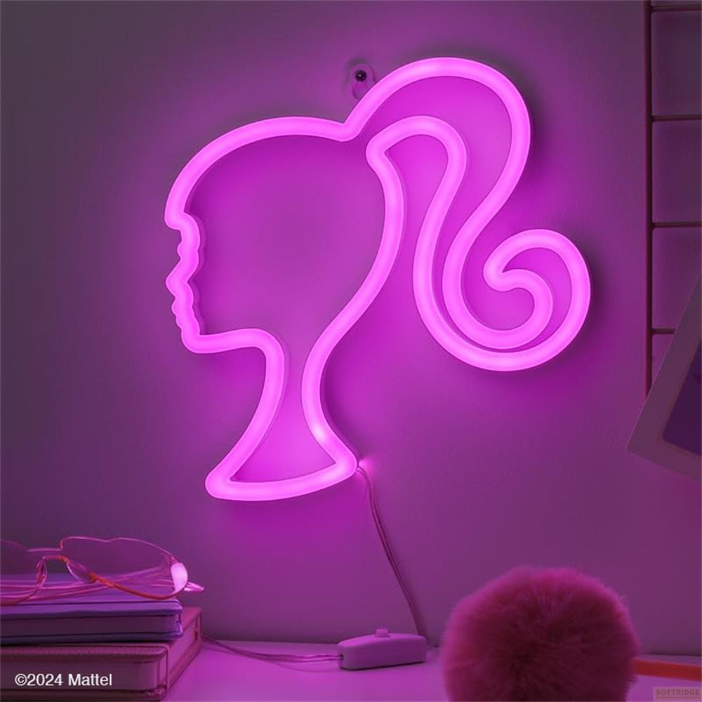 Un letrero de neón rosa con cabeza de Barbie brilla. Gafas y libro sobre la mesa.
