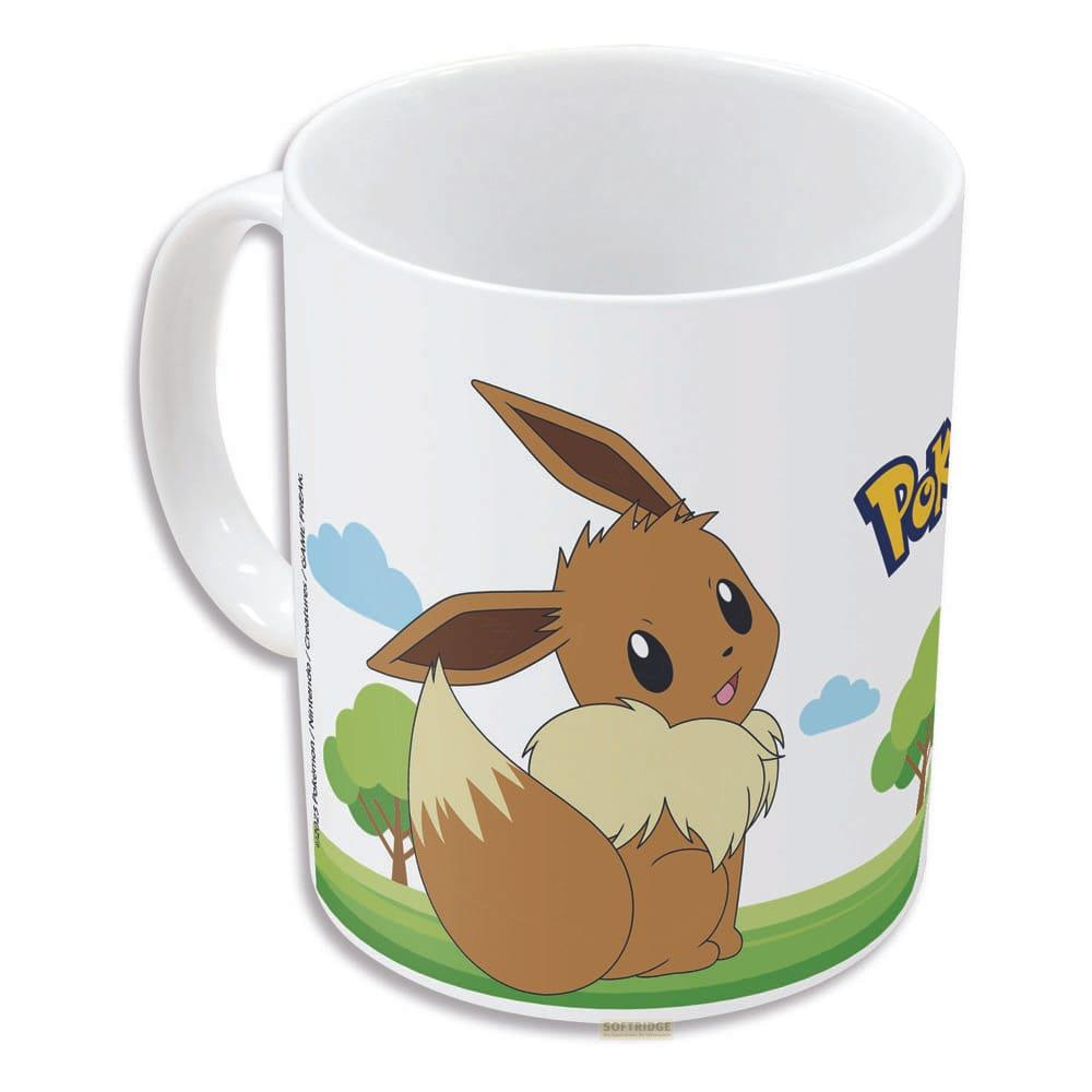 Une tasse blanche avec Evoli et le logo Pokémon dans un paysage verdoyant.