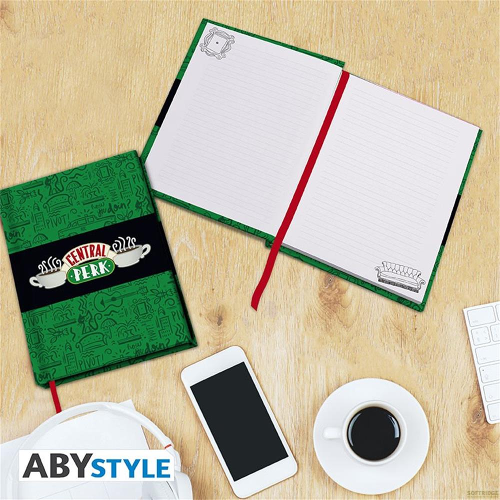 Un carnet vert avec le logo Central Perk, à côté un smartphone, des écouteurs et une tasse de café.