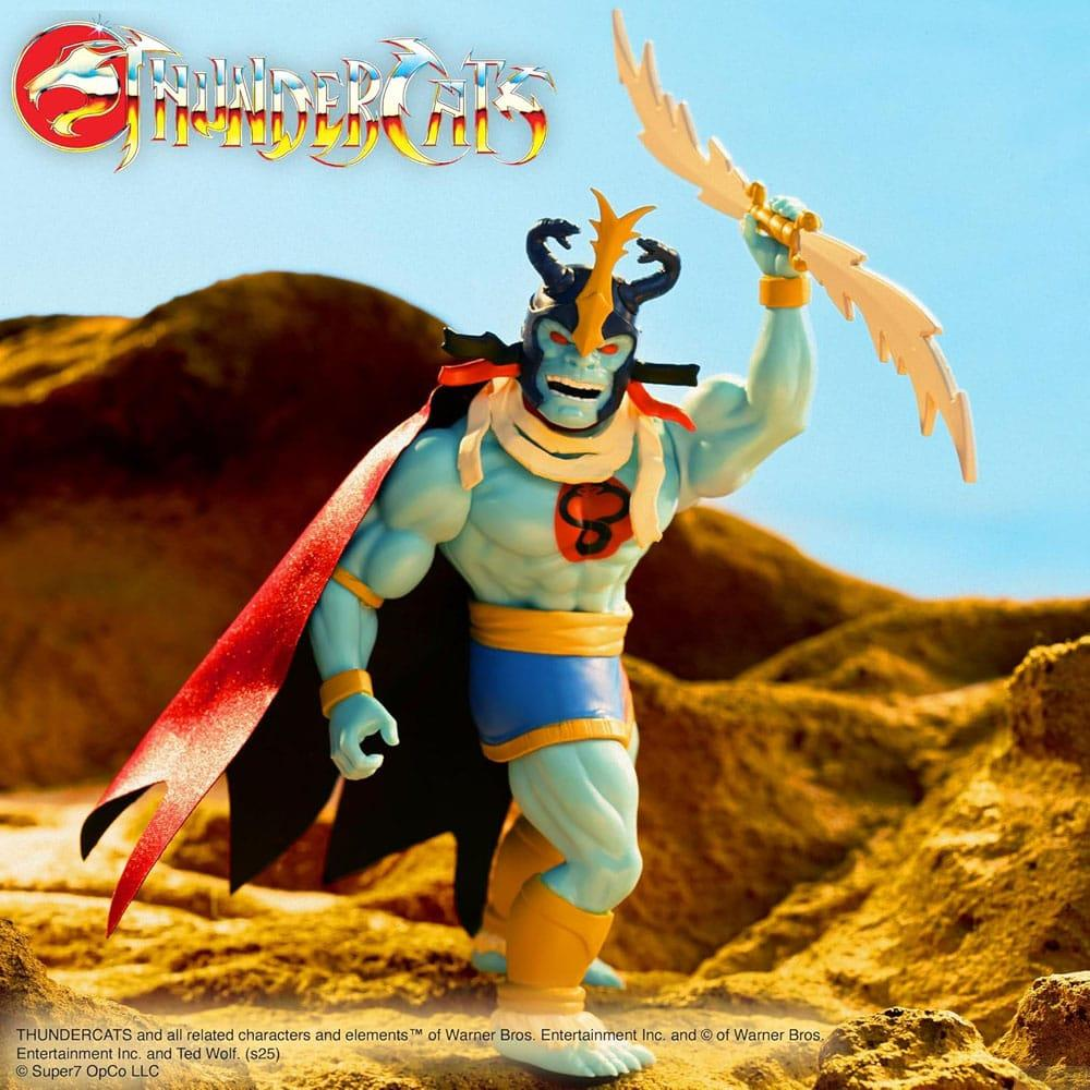 Una figura azzurra con mantello rosso tiene un bastone fulmineo in un deserto.