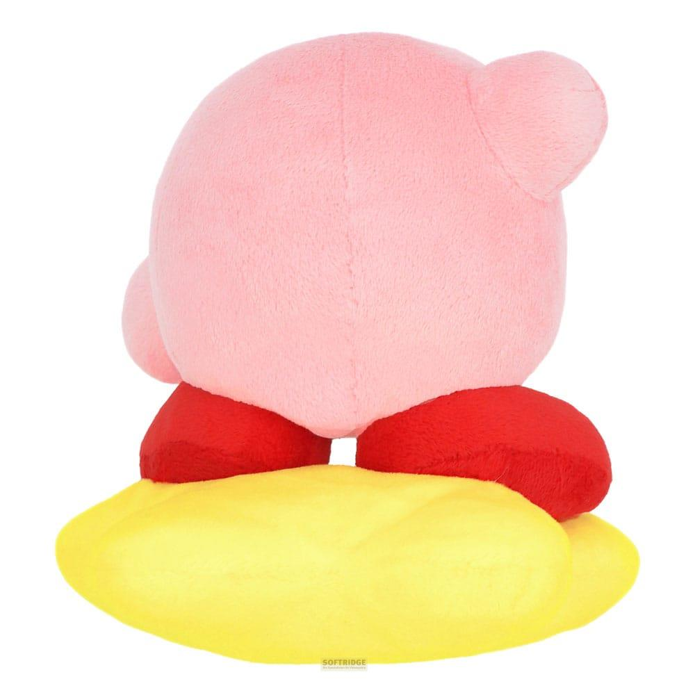 Une peluche Kirby rose se tient sur un objet jaune.