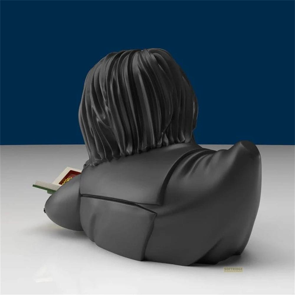 Schwarze Figur mit langen Haaren liest ein Buch auf einem weißen Tisch.