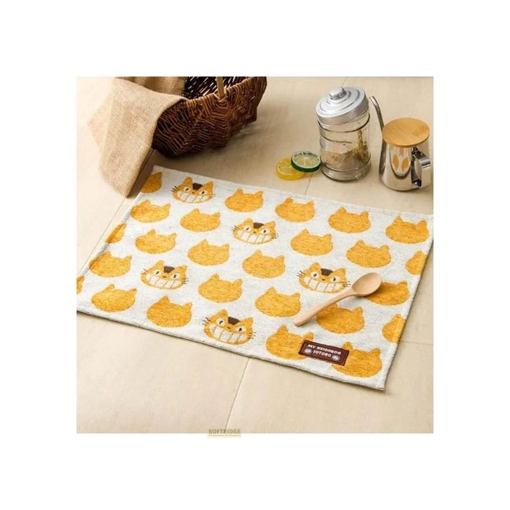 Un set de table à motif de chat Totoro, avec une cuillère en bois et un panier en arrière-plan.
