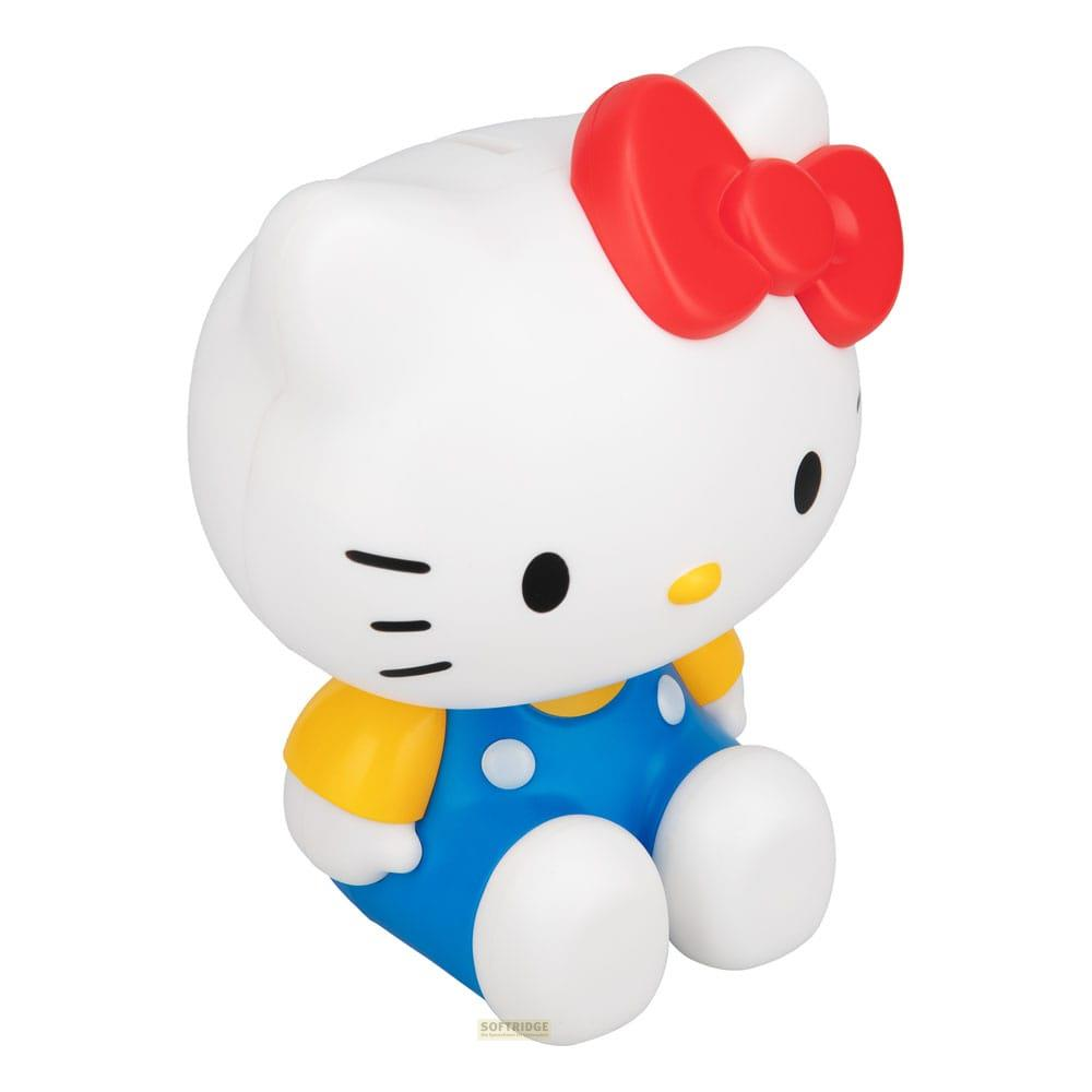 Biała figurka Hello Kitty z czerwoną kokardką, żółtą bluzką i niebieskimi ogrodniczkami.